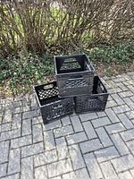 three black plastic milk crates stacked outdoors
