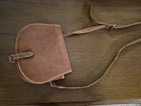 Bag front view showing leather body, buckle flap and adjustable strap