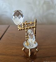 Front view of Swarovski crystal spinning wheel showing movable wheel and gold-tone frame