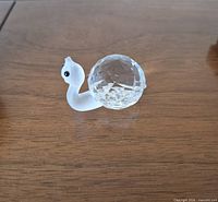 Crystal snail figurine side view on wood surface