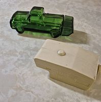 Green glass truck decanter and beige camper talc container side by side