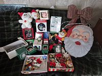 Lot overview showing illuminated Santa face, glitter bow, boxed ornaments, plush toys and loose ornaments