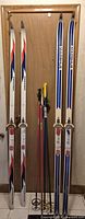 Both pairs of skis and all four poles standing against door