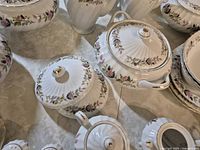 Close-up of covered tureens and teapots showing floral pattern and gold trim