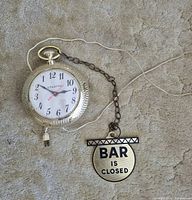Front of clock showing face and “BAR IS CLOSED” sign