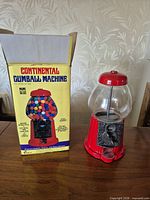 Gumball machine beside original box showing branding and components