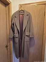 Full view of taupe-brown long overcoat on hanger