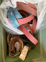 Top view of bin showing multiple looped sanding belts in various colors and grits