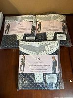 Three sealed Flora Nikrooz pajama sets displayed on table