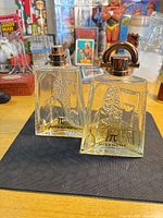 Both Givenchy Pi bottles standing on mat, showing overall design and remaining liquid levels