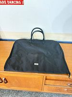 Front view of black garment bag on cabinet