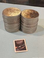 Two stacks of Canadian $1 coins beside small stamp for scale