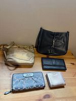 Group shot of two handbags and three wallets on tabletop