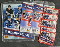 Front view of sealed album plus backer card, eight sealed sticker packs beside it