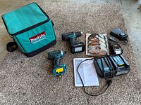 Full lot showing bag, two power tools, batteries, charger, safety glasses pack, manuals