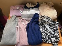 Overview of all seven sweaters and tops on table