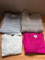 All four folded sweaters showing colors and necklines