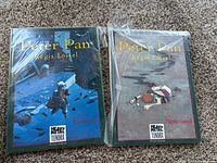 Both graphic novels front covers, shrink-wrapped