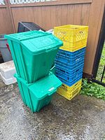 Stacked green totes with lids and stack of yellow and blue milk crates