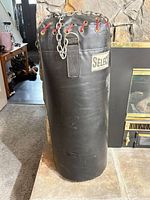 Full view of black vinyl punching bag beside fireplace