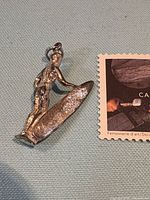 Pendant charm next to Canadian 2-cent stamp for scale