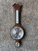 Full view of wall barometer showing thermometer, central barometer dial, lower hygrometer