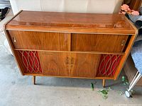 Full front view of walnut console stereo showing cabinet, speaker cloth and legs