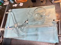 Overall view of glass distillation apparatus on blue cloth, showing both spherical chambers, coil condenser, and stopcocks