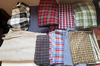 All nine folded fabric pieces laid out showing variety of plaid and gingham patterns