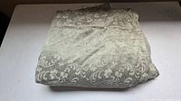 Folded bundle of beige taupe damask jacquard fabric on table