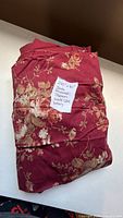 Folded length of burgundy floral microsuede fabric with handwritten size note