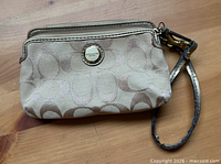 Front view of Coach wristlet showing logo badge and strap