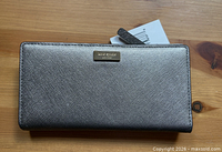 Front view of metallic silver Kate Spade wallet showing logo plate and tag