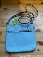 Full view of the light blue Kate Spade crossbody with strap and tag visible
