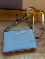 Front view of Kate Spade silver glitter crossbody bag showing logo, glitter finish and strap
