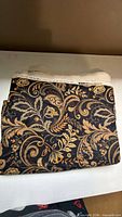 Folded floral scroll cotton canvas fabric showing overall pattern and selvage edge