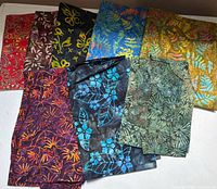 All eight batik cotton fabric pieces laid out showing color variety and patterns