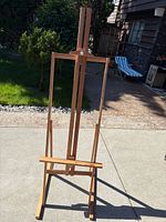 Full view of wooden studio easel standing outdoors showing overall structure and condition