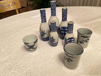 Five blue-and-white porcelain sake bottles and three cups on tabletop