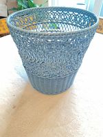 Side view of blue wicker wastebasket showing weave and color