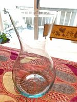 Front view of clear glass hourglass vase on patterned cloth