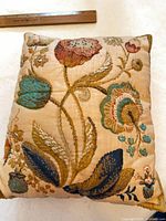 Front view of embroidered floral pillow with ruler for scale