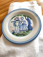 Front view showing hand-painted couple scene and blue rim