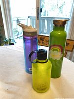 Three water bottles standing together showing size, colors and general condition