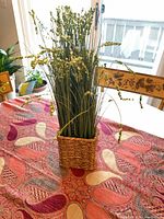 Full view of faux grass arrangement in woven basket on table