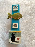 Front view showing full plaque with tiles, fish applique and painted cat beach scene