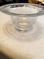 side view of clear glass bowl showing bubble inclusions and flared rim