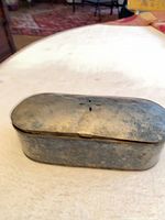 Top and side view of tarnished oval metal tin with hinged lid and vent slots