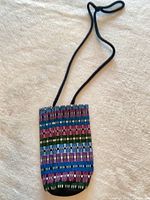 Front view of woven pouch showing strap and striped pattern