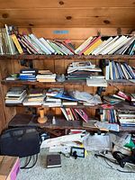 Full view of wall-mounted bookshelf filled with books, bags and loose items